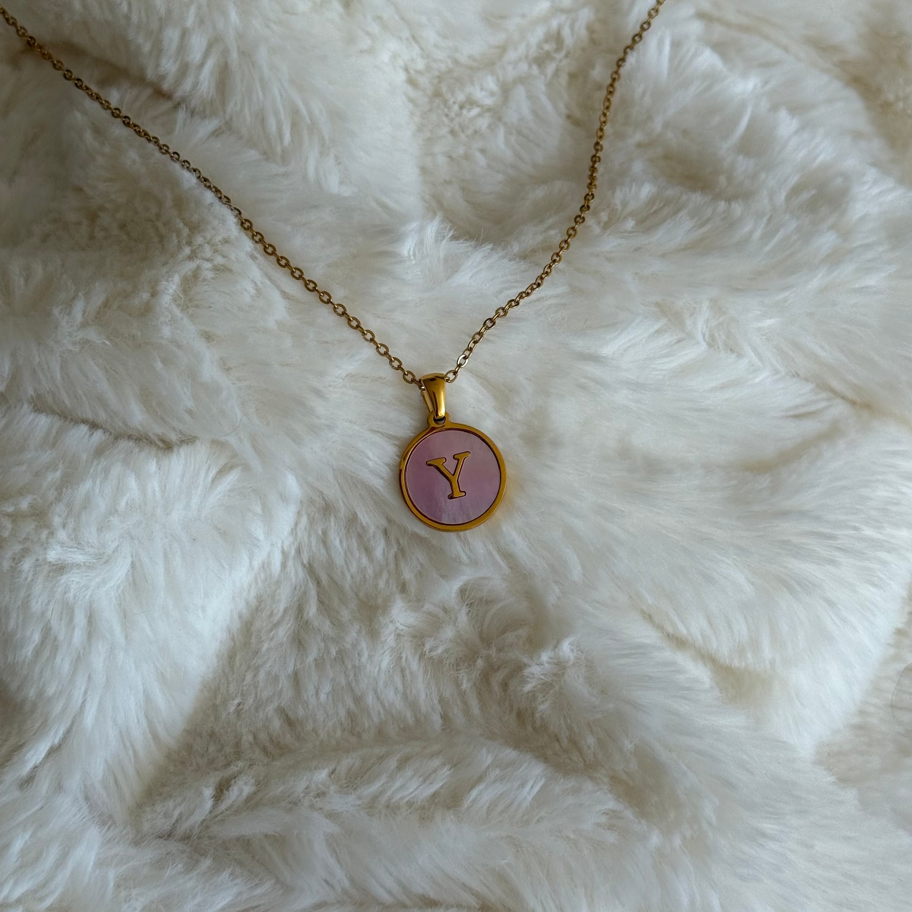 Necklace with a pink pendant featuring the letter 'Y' on a white fluffy surface