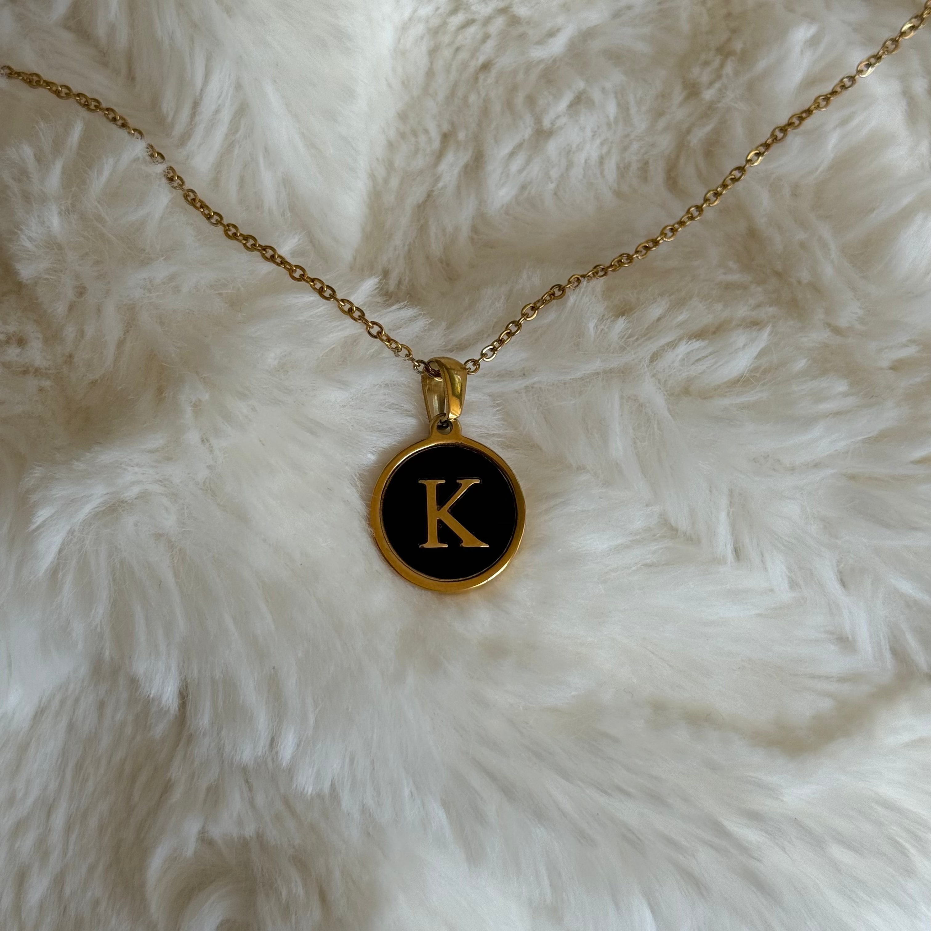 Necklace with a pendant featuring the letter 'K' on a white fur background