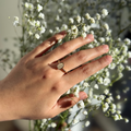 Hand wearing a ring holding a bouquet of small white flowers